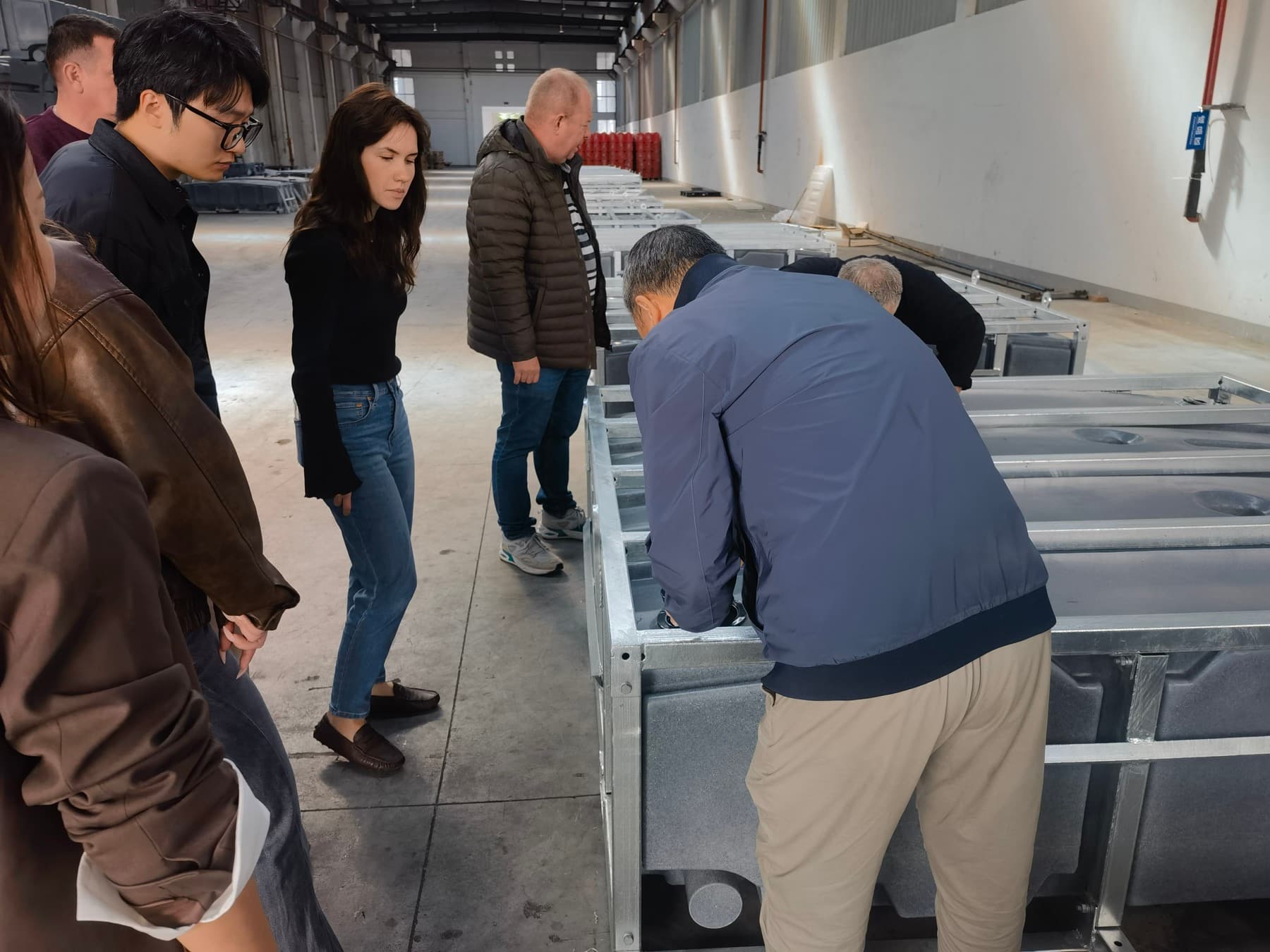 Overseas buyers inspecting portable toilet tank frames inside the Sunrise factory workshop